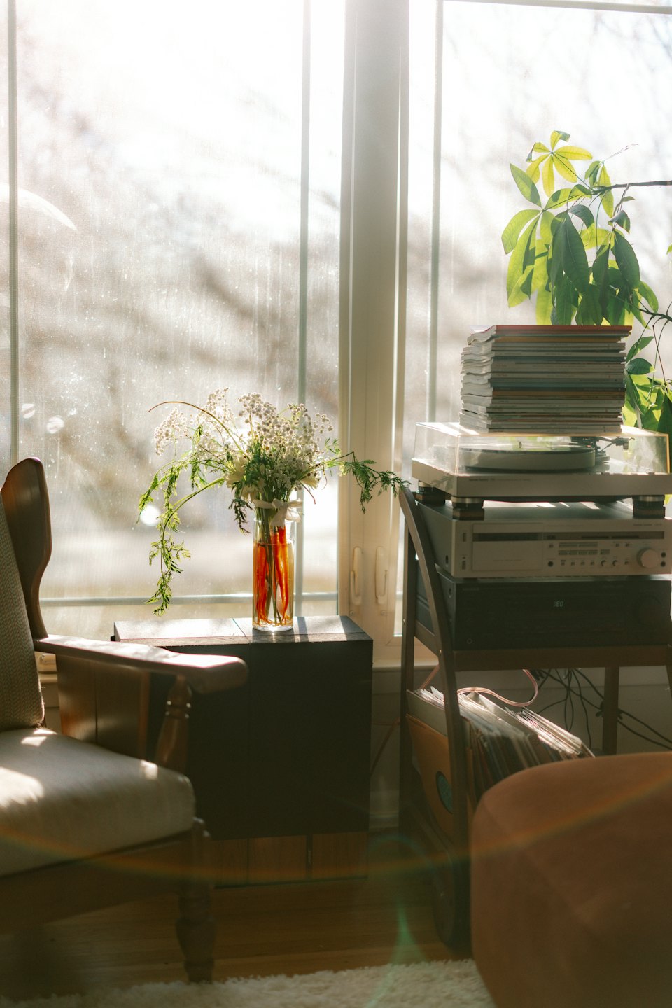 Sunlight streams on flowers and a turntable in a cozy room.